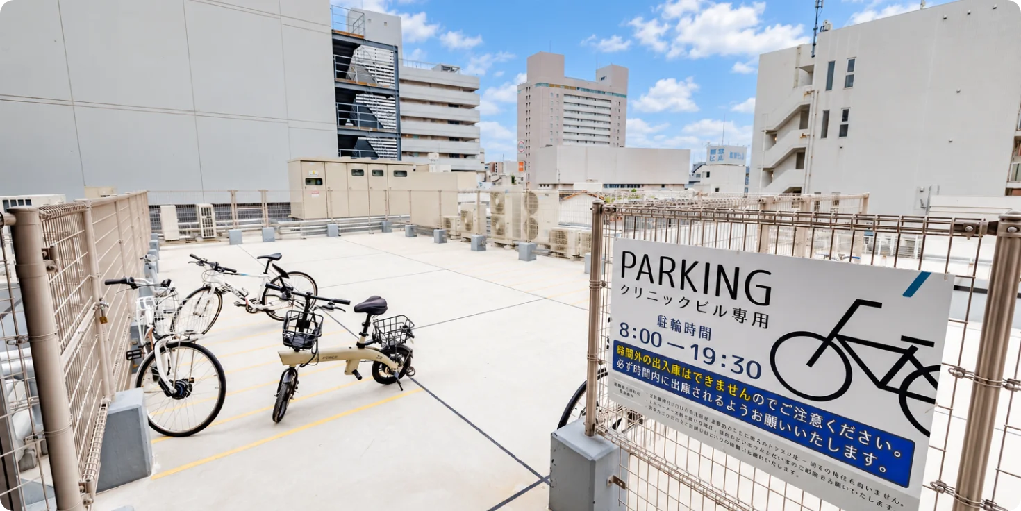 あべのウェルビーイングテラス屋上の駐輪場。「PARKING クリニックビル専用 駐輪時間 8：00－19：30」の案内板が立っている