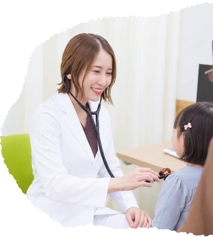 診察室で子どもを聴診する医師と付き添う保護者